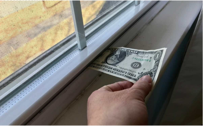 Dollar bill test showing drafty window air leakage problem