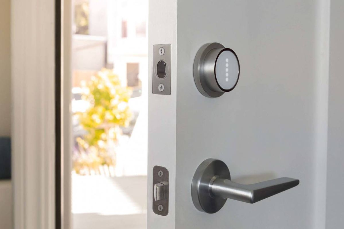 Modern smart door lock installed on white front entry