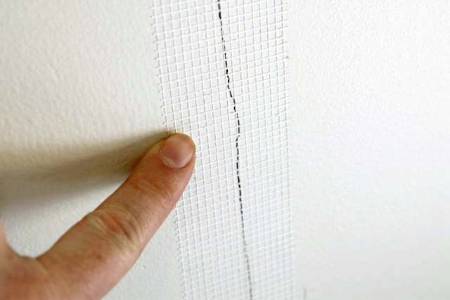Applying fiberglass mesh tape to repair drywall wall crack
