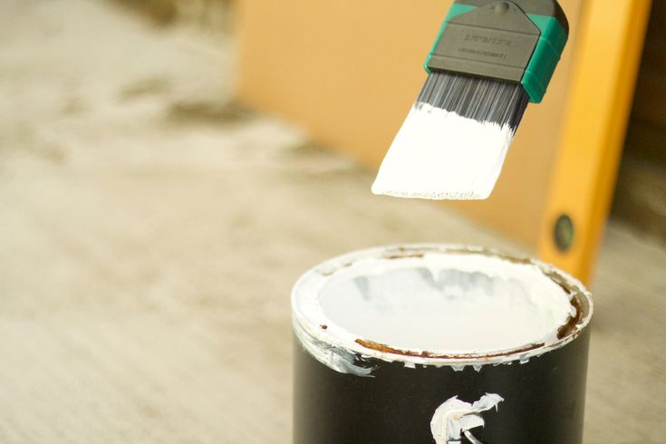 White paintbrush above open paint can during home renovation